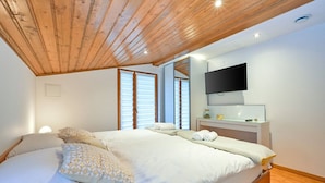 A bedroom with a wooden ceiling, a bed with white linens, a bedside table with a mirror, and a TV mounted on the wall. - Stunning Villa with infinity pool, Croatia (Donja Poljana)