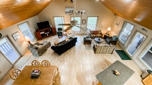 Een ruime loft met een hoge plafond, een eethoek met een houten tafel en stoelen, een keuken met een granieten werkblad, en een woonkamer met diverse zitmogelijkheden en een televisie.