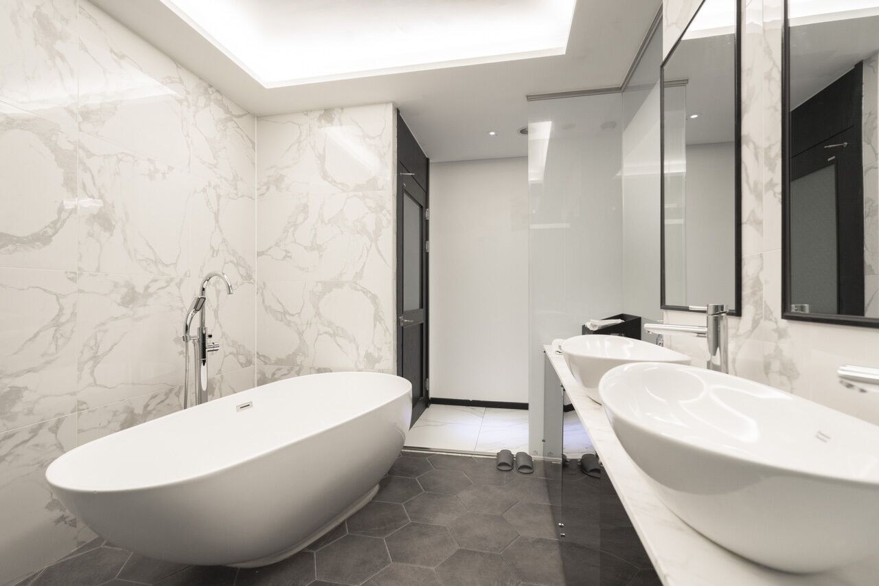 A modern bathroom with a freestanding bathtub, two sinks, and a large mirror.