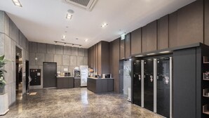 Een moderne hotelentree met een receptiebalie, een koelkast en een schone, betegelde vloer.