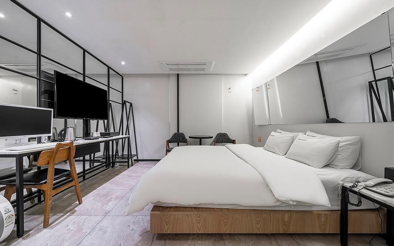Una habitación de hotel moderna con cama, escritorio, silla y televisor de pantalla plana.