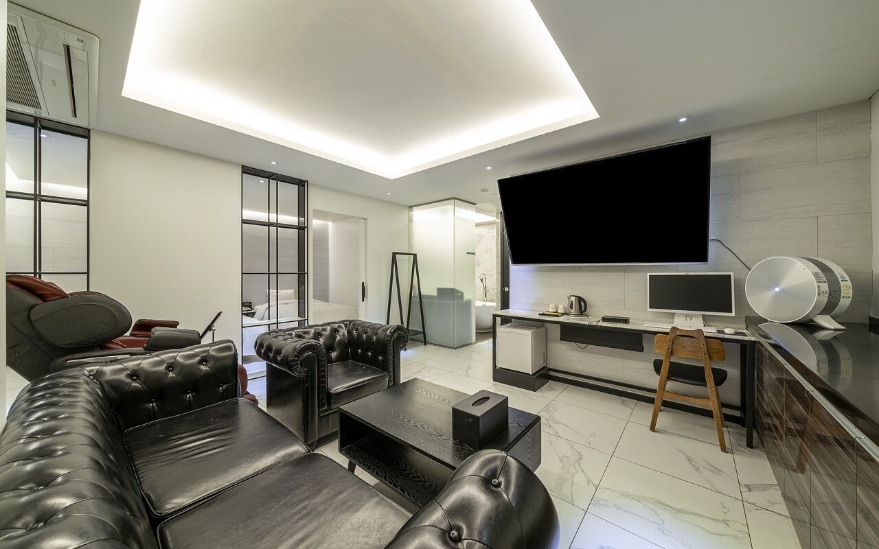 Una sala de estar moderna con un sofá seccional, un televisor de pantalla plana, un comedor y una cocina.