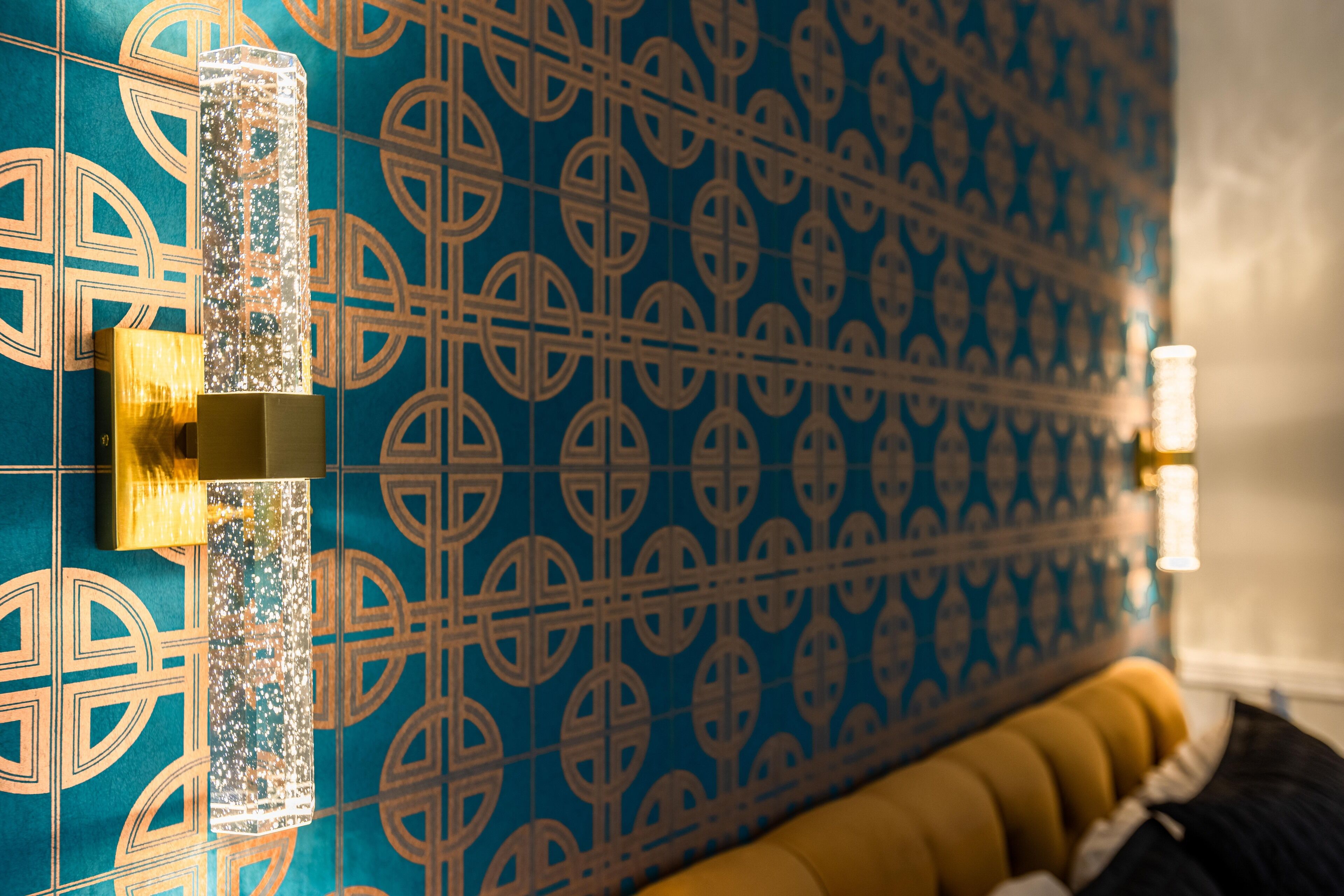 A patterned wall with a decorative column and a sofa with cushions.