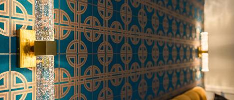 A patterned wall with a decorative column and a sofa with cushions.