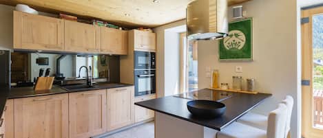 Una cocina moderna con armarios de madera, encimera negra y una isla grande con taburetes de bar.