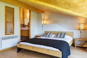Une chambre à coucher avec un lit en bois, deux tables de chevet, une commode, un miroir et une étagère intégrée.
