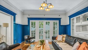 A living room with a black leather sofa, a wooden coffee table, and a blue accent wall. - A Huge, Calm, Relaxing, Beautiful Home close to Universal Studio (Pasadena)