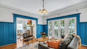 A living room with a wooden coffee table, a black leather sofa, and a blue accent wall. - A Huge, Calm, Relaxing, Beautiful Home close to Universal Studio (Pasadena)