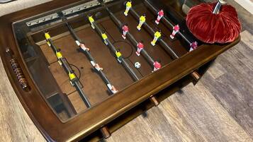 A wooden foosball table with a red pom-pom on one end.