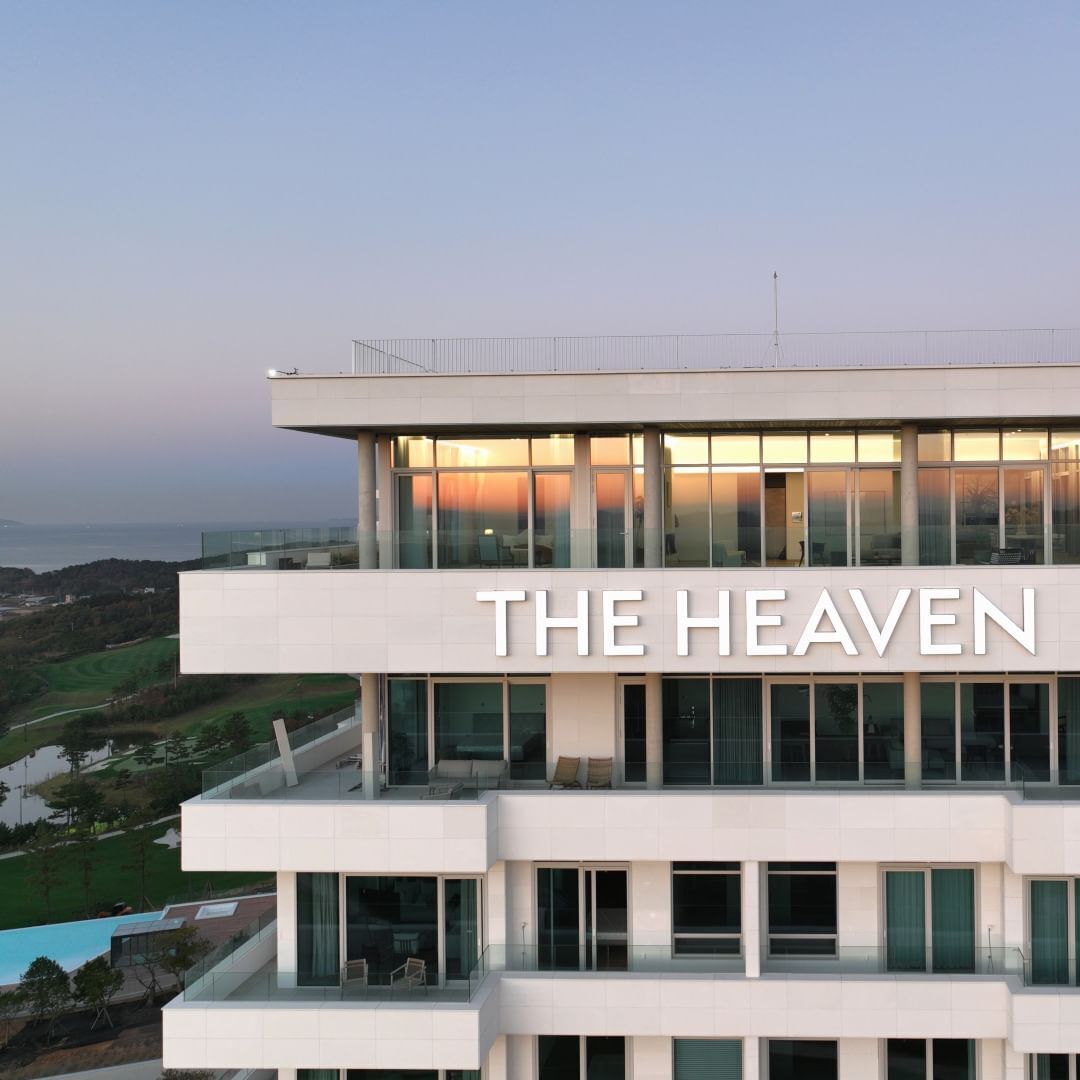 Un bâtiment moderne sur lequel on peut lire en grand « THE HEAVEN ». Il se compose de plusieurs étages, dotés de grandes fenêtres et de balcons.