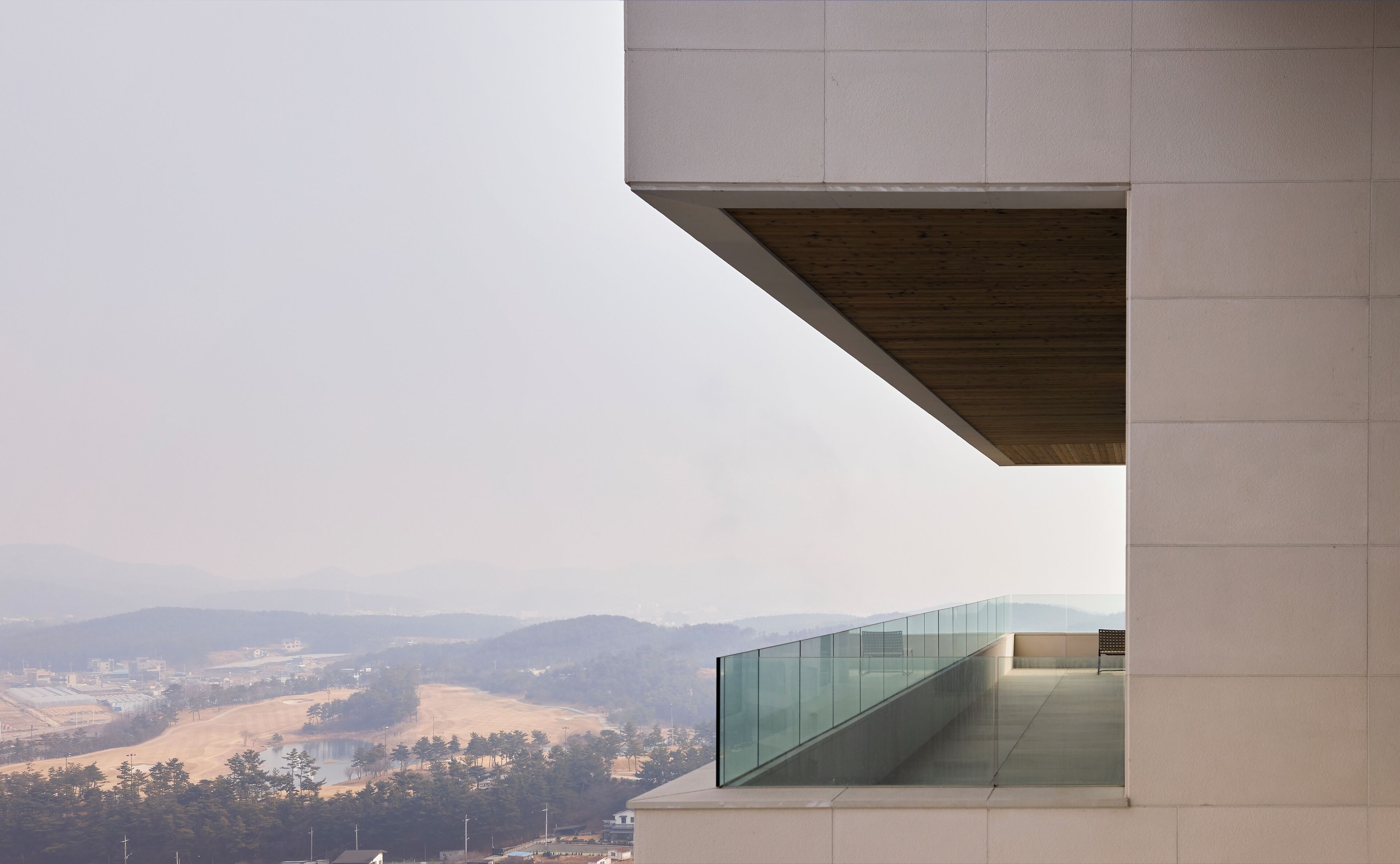 Un bâtiment moderne doté d’un balcon en verre donnant sur une vallée.