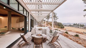 A wooden deck with wicker furniture and a fire pit, overlooking a scenic landscape. - The Heaven Resort (Ansan)