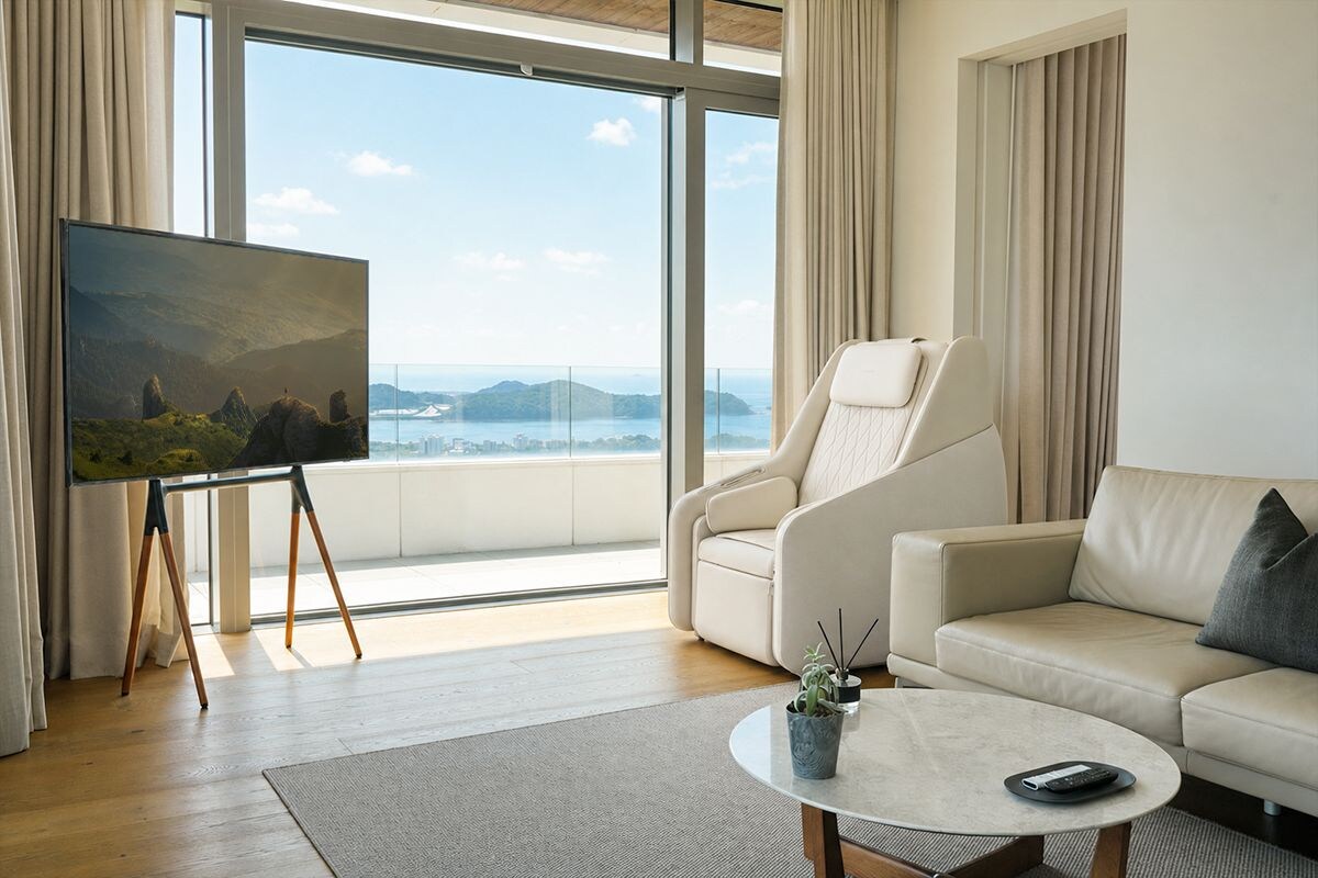 Ein modernes Wohnzimmer mit einem großen Fenster, einem Sofa, einem Couchtisch und einem Gemälde auf Staffeleien.