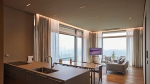 A modern kitchen with a large island, dining area with a TV, and a seating area with a view. - The Heaven Resort (Ansan)
