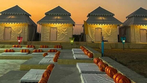 A row of yurts with a pathway leading to them, under a twilight sky.