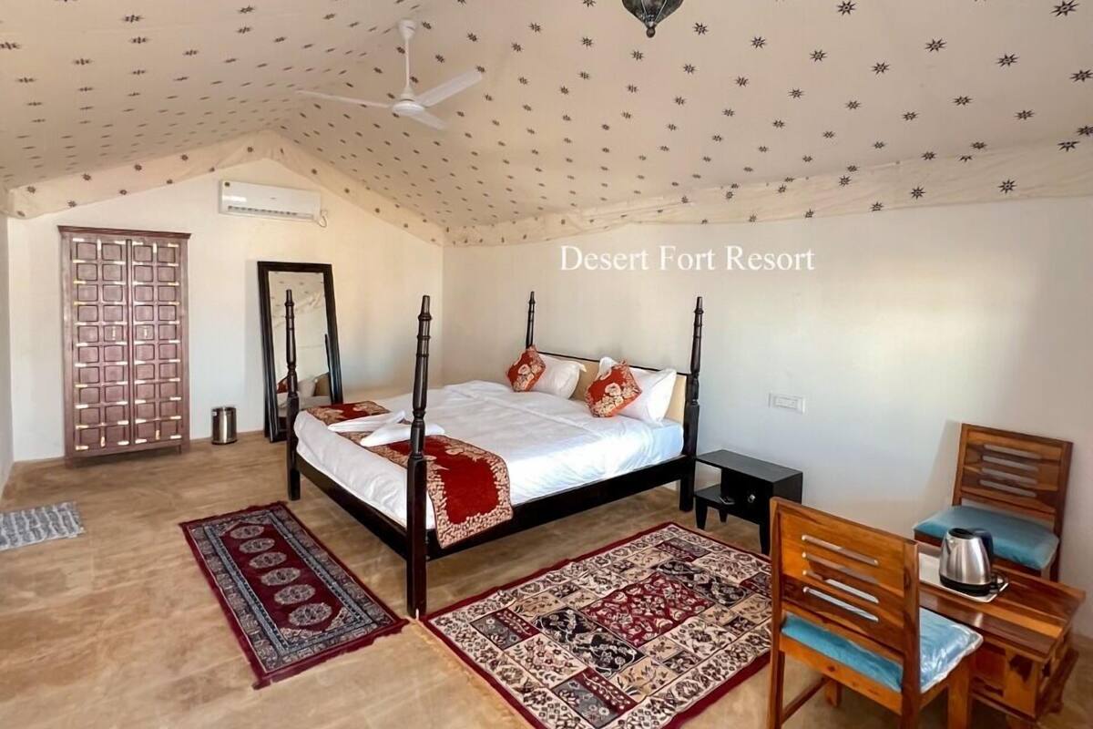 Un dormitorio con cama con dosel, una silla de madera, una mesita pequeña y una lámpara colgante decorativa.