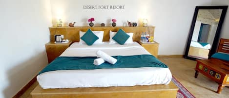 A hotel room with a large bed, a headboard with decorative items, a nightstand with a lamp, and a mirror on the wall.