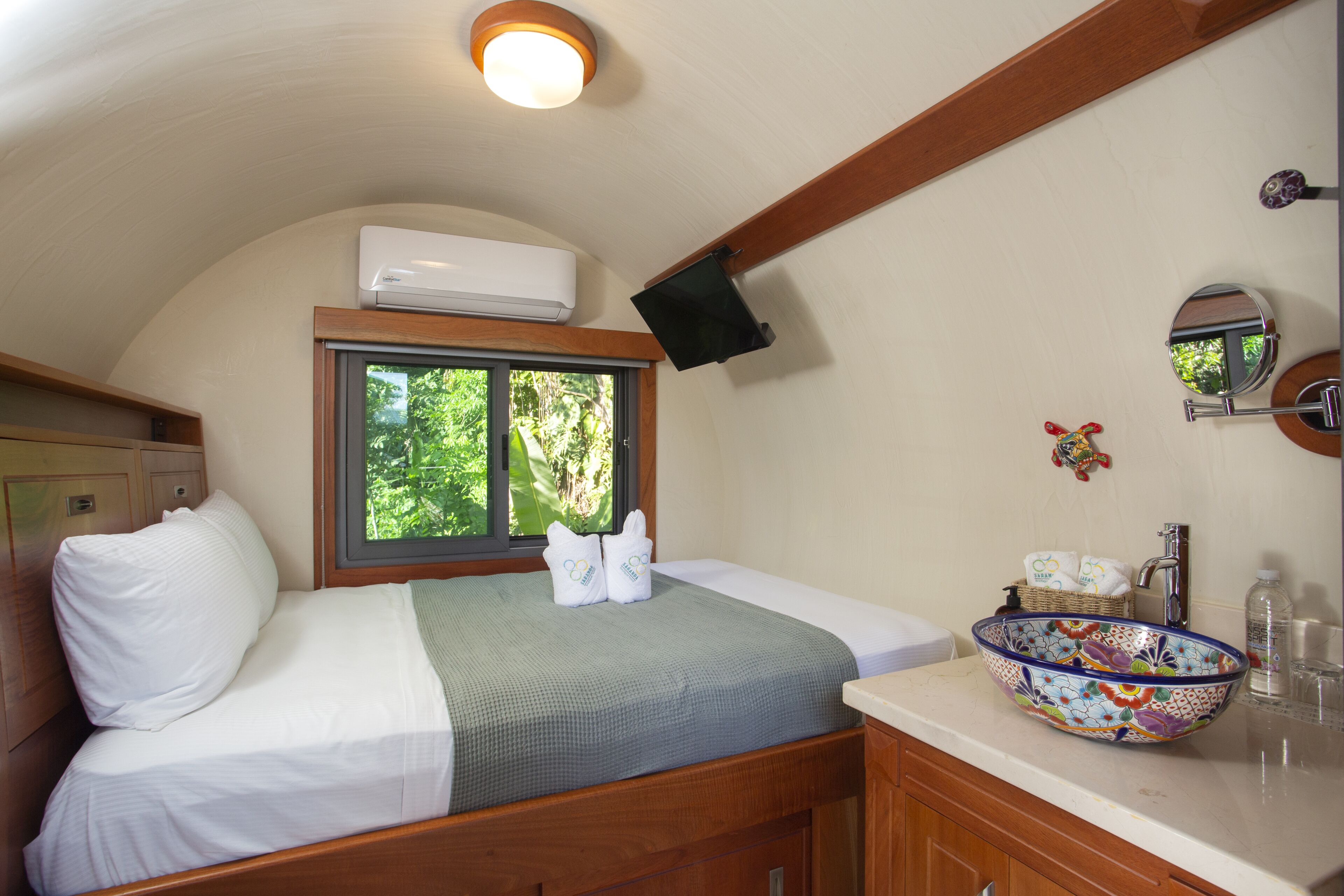 Un dormitorio con cama, ventana, lavabo y espejo.