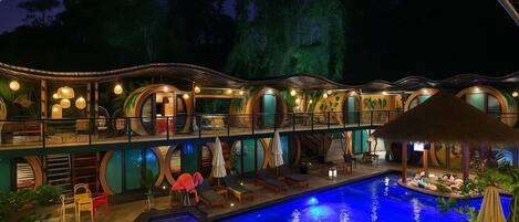 Et resort med pool, loungeområder og en struktur med stråtækte tag.