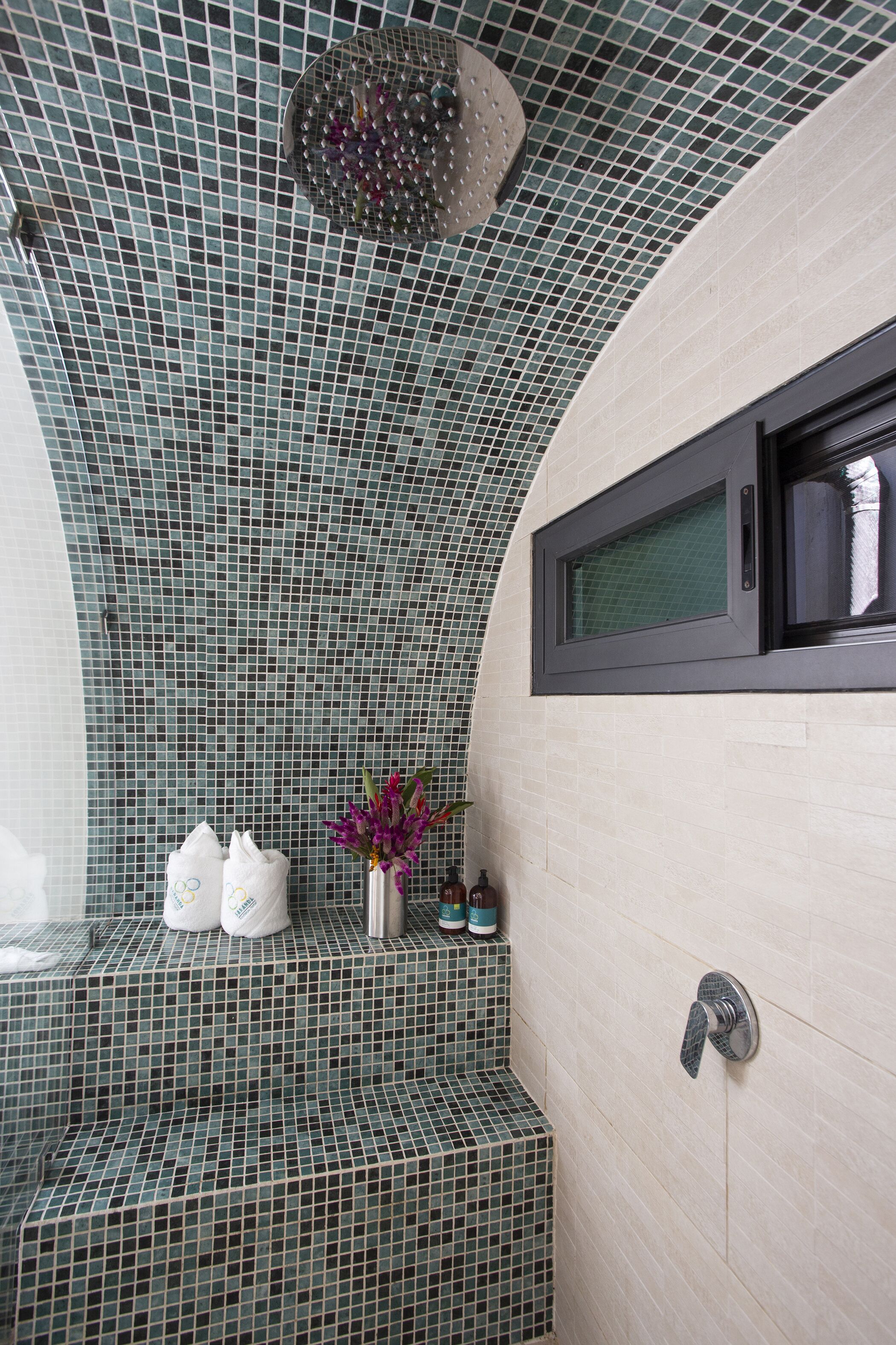 Une salle de bain avec un plafond décoré de mosaïques, un espace douche et un porte-serviettes avec des serviettes.
