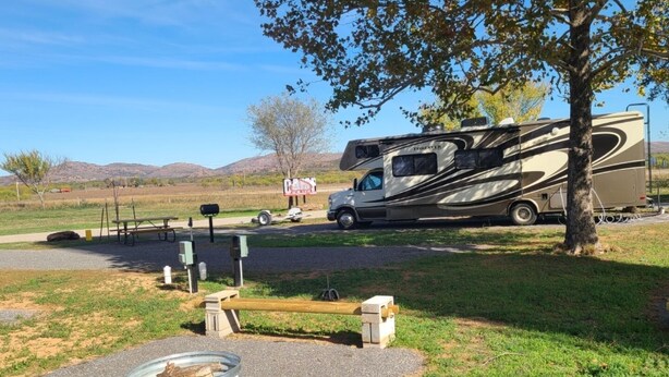 A campsite with a large RV, picnic tables, and a fire pit area. - Campsite near Wichita Wildlife Refuge & Mountains (Cache)