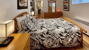 Ein Schlafzimmer mit Bett, Nachttisch, Lampe, Kommode und Spiegel.