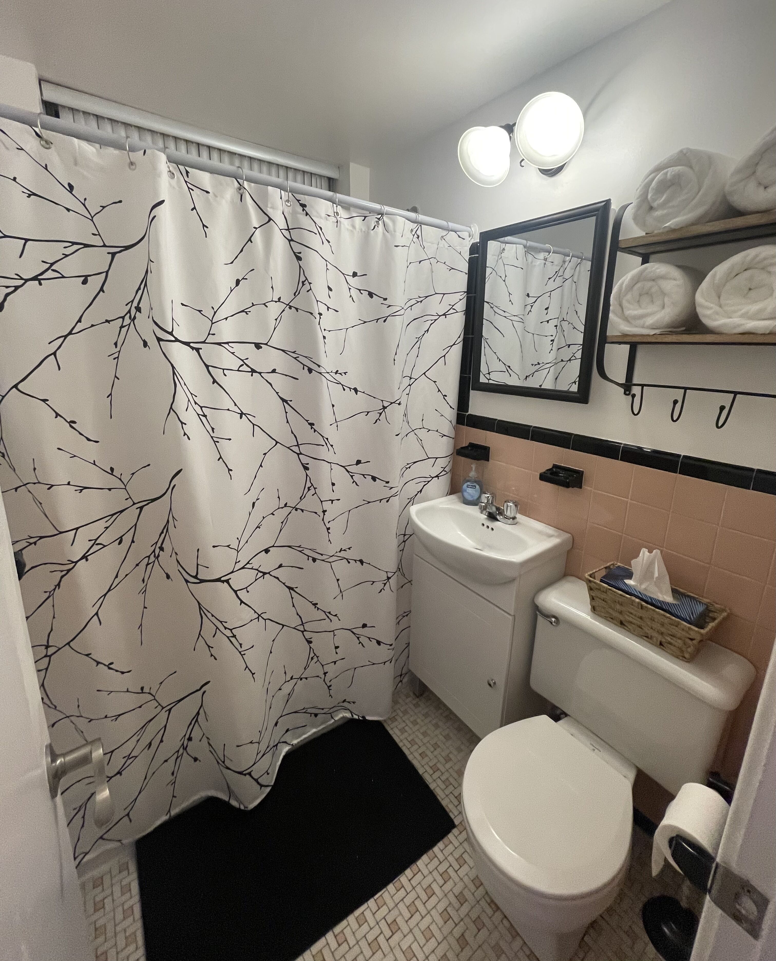 A small bathroom with a toilet, sink, and a shower curtain with a branch pattern.