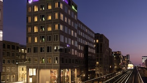 Un hotel moderno con varios pisos, grandes ventanales y señalización iluminada.