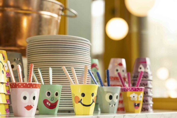 Tazas coloridas con caras y pajitas a rayas sobre una mesa.