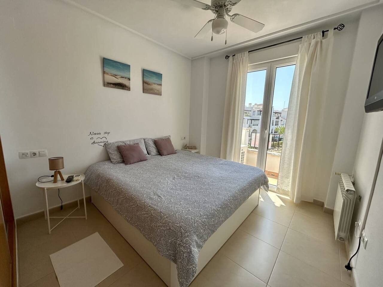 A bedroom with a bed, a nightstand, a lamp, and a window with curtains.