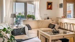 Una sala de estar moderna con un sofá, una mesa de centro y una zona de bar con taburetes.