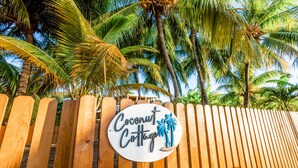 Une clôture en bois avec une pancarte indiquant « Coconut Cottage ».