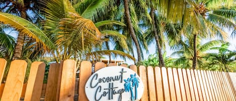 A wooden fence with a sign that reads "Coconut Cottage."