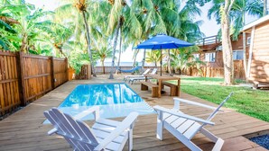 Une terrasse en bois avec une piscine, des chaises longues et un hamac.