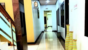 A hotel hallway with a clock, a welcome sign, and a staircase. - Rizh Hotel (Bandung)