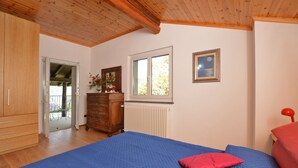 Ein Schlafzimmer mit Holzboden, einem großen Bett mit blauer Bettwäsche, einem Schminktisch, einem Fenster mit Blick und einer Heizung.