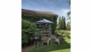 An outdoor seating area with a table and chairs, a barbecue grill, and a pergola. - Cocooning air-conditioned gîte in a privileged, peaceful setting with large swimming pool (Bougé-Chambalud)