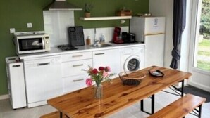 A modern kitchen with white cabinets, a wooden table with benches, a microwave, a coffee maker, and a sink. - Cocooning air-conditioned gîte in a privileged, peaceful setting with large swimming pool (Bougé-Chambalud)