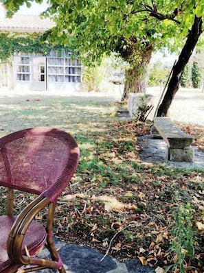 Relax in a serene outdoor seating area surrounded by lush greenery and a charming building in the background.
