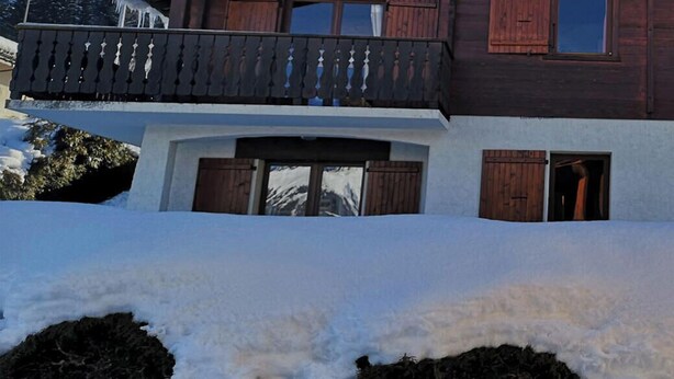 Un chalet en bois à deux étages, doté d’un balcon, portant l’inscription « LES MOUFLONS ALT 1220 ».