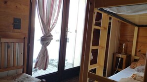 Une pièce de cabane en bois comprenant un lit, un banc et une fenêtre avec des rideaux.