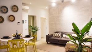 A modern living room with a brown sofa, yellow chairs, and a dining table set for four.