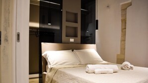 A neatly made bed with a quilted cover, a headboard, and two pillows. There is a towel on the bed.