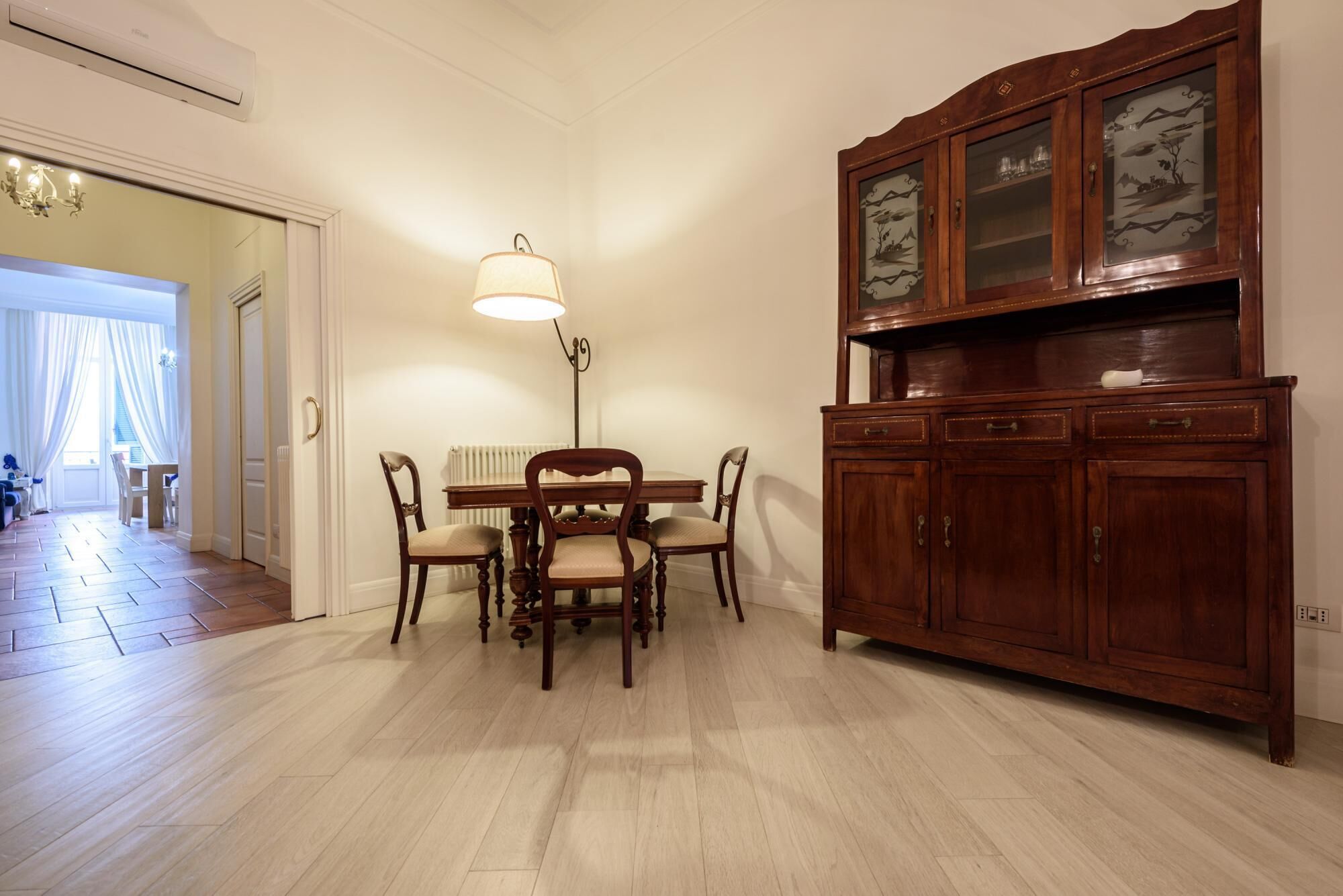 A dining area with a wooden table and chairs, a chandelier, and a wooden cabinet with glass doors.