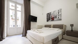 A bedroom with a bed, a flat-screen TV, a bedside table, and a window with curtains. - Palazzo Dello Spagnolo Suite (Naples)