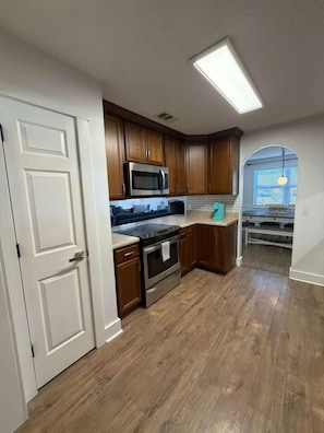 A kitchen with wooden cabinets, a stainless steel microwave, and a black stove. - ⭐️La Puerta Al cielo - Private Pool, Game Room & Kareoke (Pensacola)