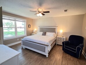 Relax in this serene bedroom with a large bed, tufted headboard, and comfortable seating area.