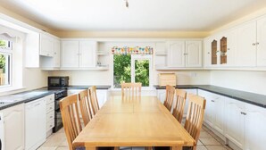 A spacious kitchen with white cabinets, a wooden dining table, and a view of greenery outside. - An Rua (500m to Lahinch Beach), An Rua - 15 min walk to Lahinch Golf Club (Lahinch Road)