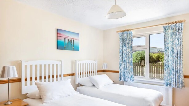 A room with two single beds, a window with curtains, a painting on the wall, and a lamp on the nightstand. - An Rua (500m to Lahinch Beach), An Rua - 15 min walk to Lahinch Golf Club (Lahinch Road)