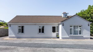 A single-story house with a tiled roof, white exterior walls, and a small porch area. - An Rua (500m to Lahinch Beach), An Rua - 15 min walk to Lahinch Golf Club (Lahinch Road)